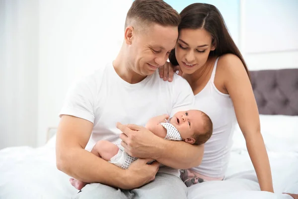 Lyckliga paret med sin nyfödda baby på säng — Stockfoto