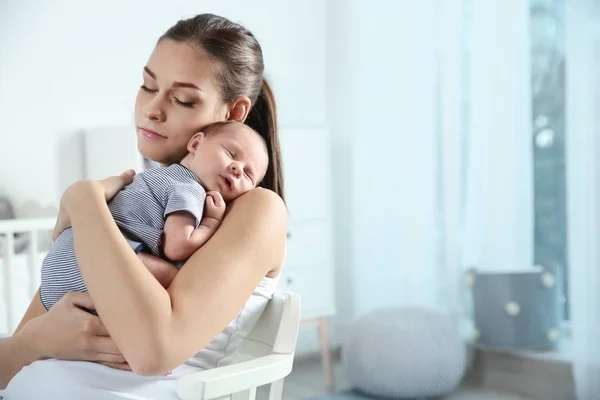 Mujer joven con su bebé recién nacido en casa. Espacio para texto — Foto de Stock