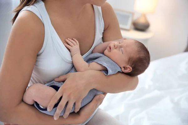 Mladá žena držící své dítě u prsu v ložnici, closeup — Stock fotografie