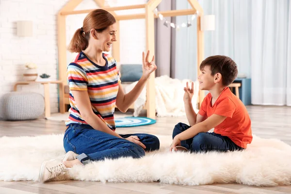 La madre con discapacidad auditiva y su hijo hablan con ayuda del lenguaje de señas en el interior — Foto de Stock