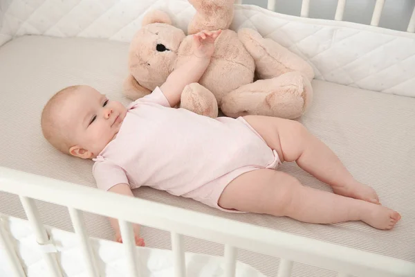 可爱的女婴与玩具在婴儿床。睡觉时间时间表 — 图库照片