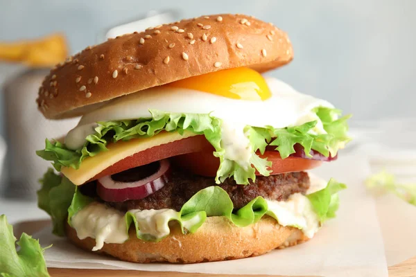 Hamburger gustoso con uovo fritto su tavola di legno — Foto Stock