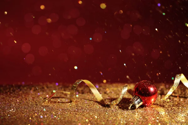 Golden glitter, Christmas ball and streamer against color background. Space for text