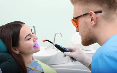 Profesyonel diş hekimi modern klinik hasta ile çalışma. Diş beyazlatma