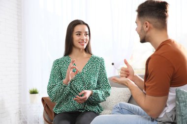 İşitme engelli arkadaşlar oturma odasında kanepede iletişim için işaret dili kullanarak
