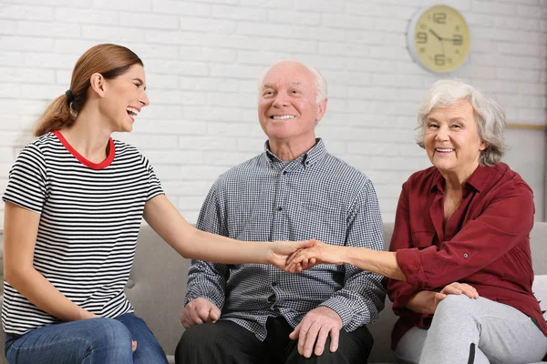 Bejaarde echtpaar met vrouwelijke verzorger thuis — Stockfoto