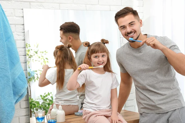 Menina e seu pai escovando os dentes juntos no banheiro em casa — Fotografia de Stock