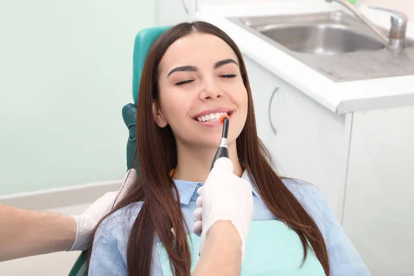 プロの歯科医師が近代的な医院では、患者での作業します。歯のホワイトニング — ストック写真