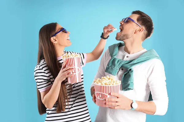 Casal com óculos 3D e pipoca saborosa no fundo de cor — Fotografia de Stock