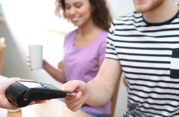 Clients using credit card machine for non cash payment in cafe, closeup