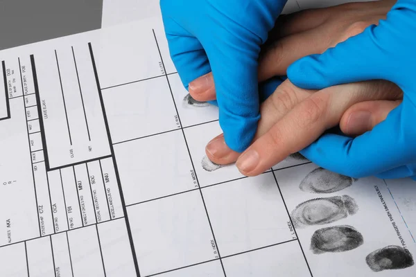 Следователь снимает отпечатки пальцев подозреваемого за столом, крупным планом. Криминальная экспертиза — стоковое фото
