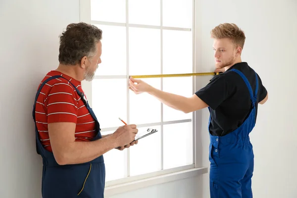 Служащие измеряют окно для установки в помещении — стоковое фото