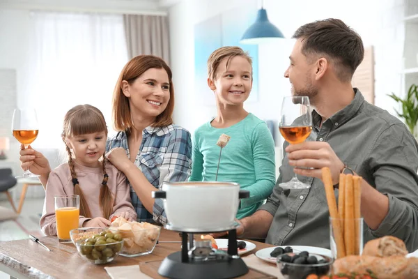 Família feliz desfrutando de jantar fondue em casa — Fotografia de Stock