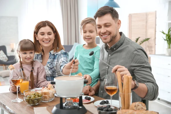 Šťastná rodina těší fondue večeře doma — Stock fotografie