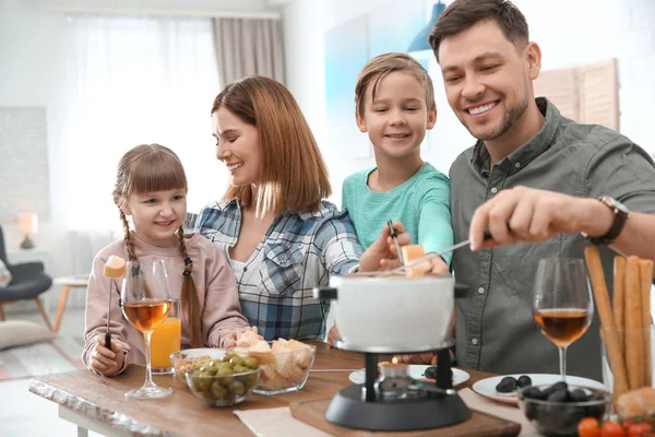 Família feliz desfrutando de jantar fondue em casa — Fotografia de Stock