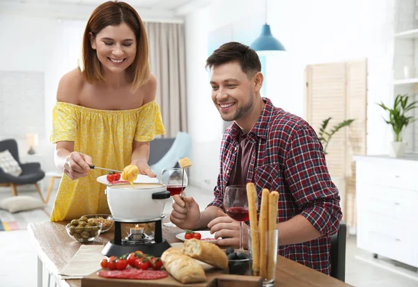 Šťastný pár, kteří požívají fondue večeře doma — Stock fotografie