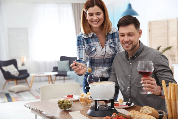 Šťastný pár, kteří požívají fondue večeře doma — Stock fotografie