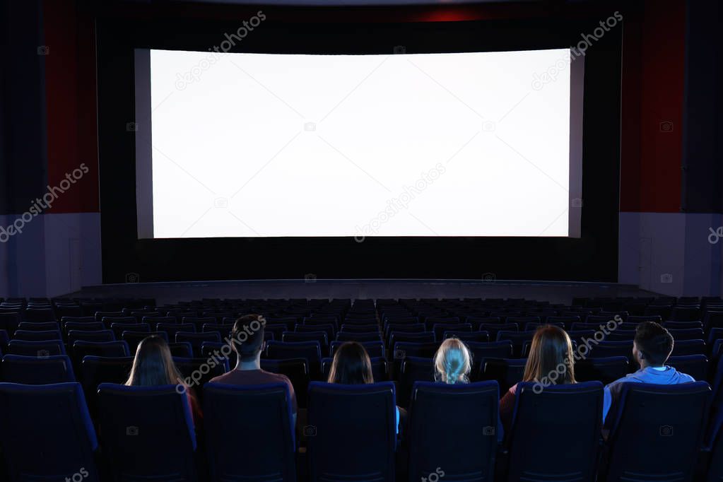 Young people watching movie in cinema theatre. Space for text