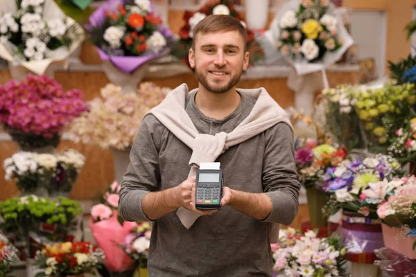 Seller holding payment terminal in floral shop