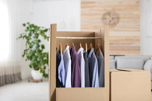 Armario de cartón con ropa en perchas en la sala de estar — Foto de Stock