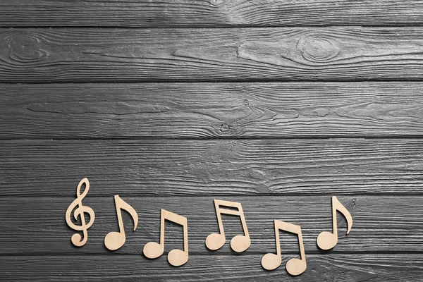 Music notes and treble clef on wooden background, top view. Space for text — Stock Photo, Image