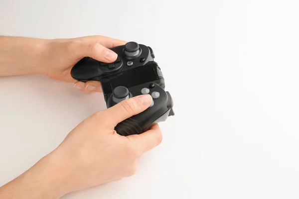 Jovem segurando controlador de jogo de vídeo no fundo branco, close-up — Fotografia de Stock