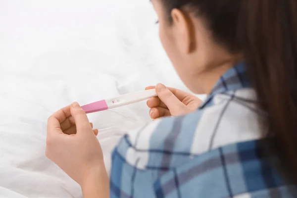 Młoda kobieta z test ciążowy na łóżku, zbliżenie. Ginekologia i poród — Zdjęcie stockowe