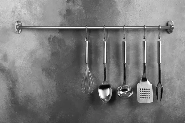 Bastidor con utensilios de cocina limpios en la pared gris. Espacio para texto — Foto de Stock