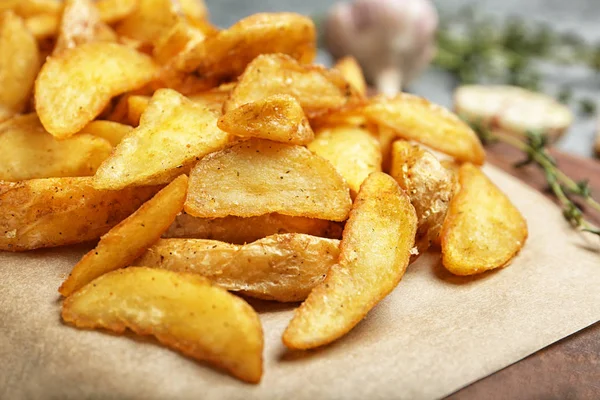 Deliciosas fatias de batata assadas em pergaminho, close-up — Fotografia de Stock