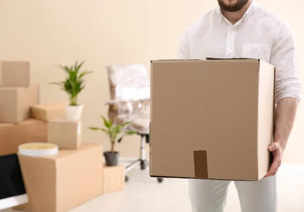 Un homme tenant une boîte de déménagement dans un nouveau bureau, gros plan. Espace pour le texte — Photo