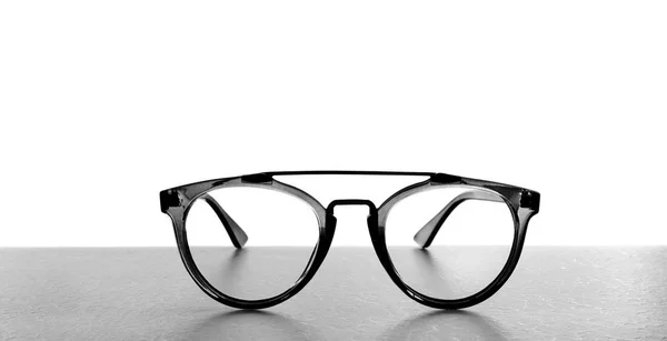 Óculos em mesa cinza contra fundo branco. Consulta oftalmológica — Fotografia de Stock