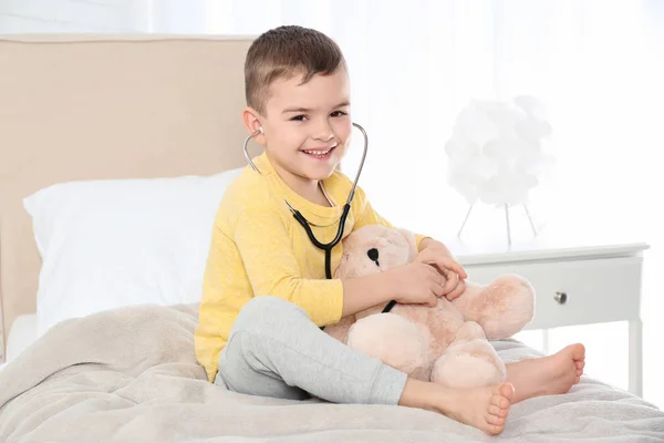 Słodkie dziecko grając z lekarzem z nadziewane zabawka w szpitalu — Zdjęcie stockowe
