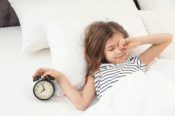Cute little girl with alarm clock awaking in bed. Healthy sleep — Stock Photo, Image