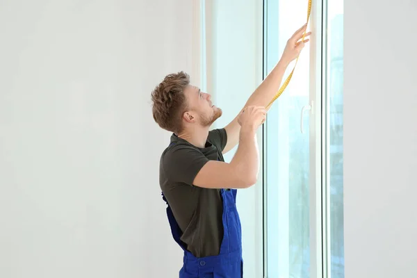 Service man measuring window for installation indoors