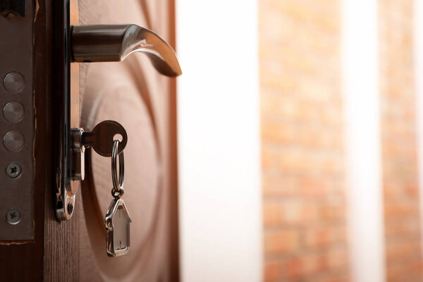 Ключ с домашней безделушкой в дверном замке, вид крупным планом
