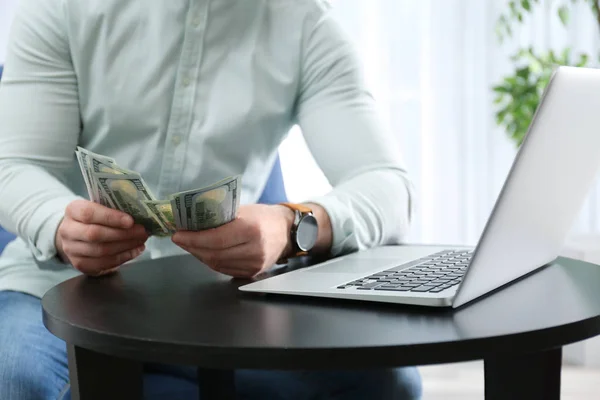 Бизнесмен с ноутбуком и деньгами за столом в помещении, крупным планом — стоковое фото