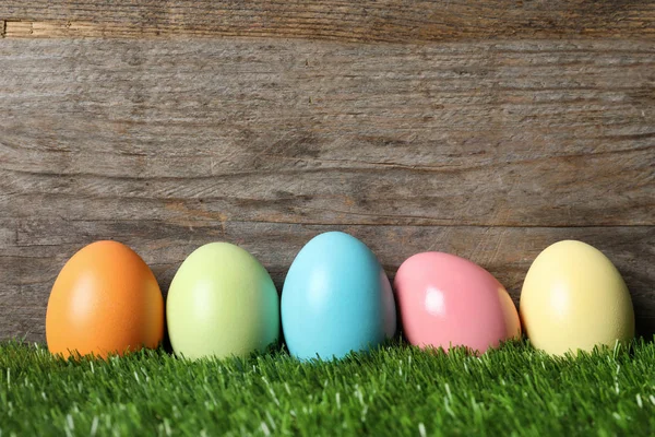 五颜六色的染色复活节彩蛋在绿草对木背景, 文本空间 — 图库照片