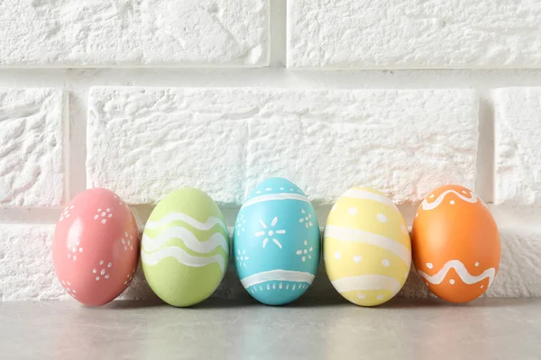 Renkli Paskalya yumurtaları tuğla duvar, metin için yer yakınındaki masada boyalı — Stok fotoğraf