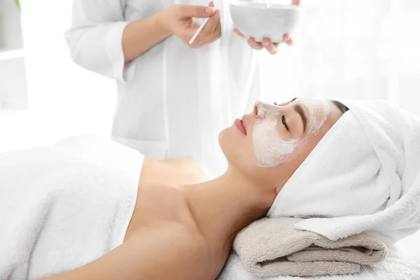 Jolie femme avec masque sur le visage dans le salon de spa — Photo