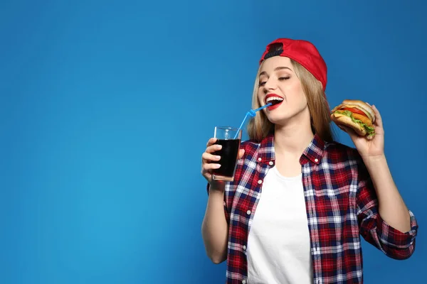 Mujer bonita con sabrosa hamburguesa y cola sobre fondo de color. Espacio para texto —  Fotos de Stock