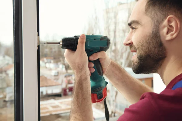 Trabalhador da construção usando broca durante a instalação de janela dentro de casa, close-up — Fotografia de Stock