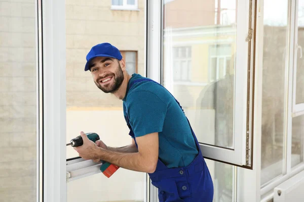 Byggnadsarbetare med borren medan du installerar fönster inomhus — Stockfoto