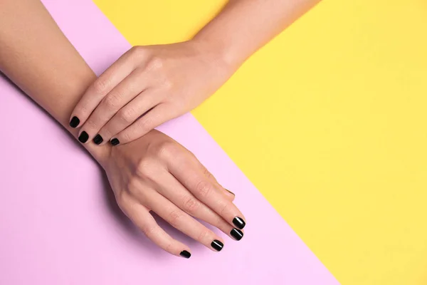 Mujer con manicura negra sobre fondo de color, vista superior y espacio para texto. Tendencias de esmalte de uñas —  Fotos de Stock