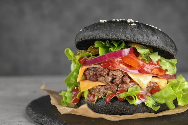 Πλάκα πλάκα με μαύρο burger στο τραπέζι, κινηματογράφηση σε πρώτο πλάνο. Χώρο για το κείμενο — Φωτογραφία Αρχείου