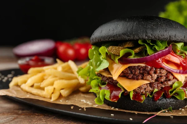 Deska s černým burger a hranolky na stole, closeup. Prostor pro text — Stock fotografie