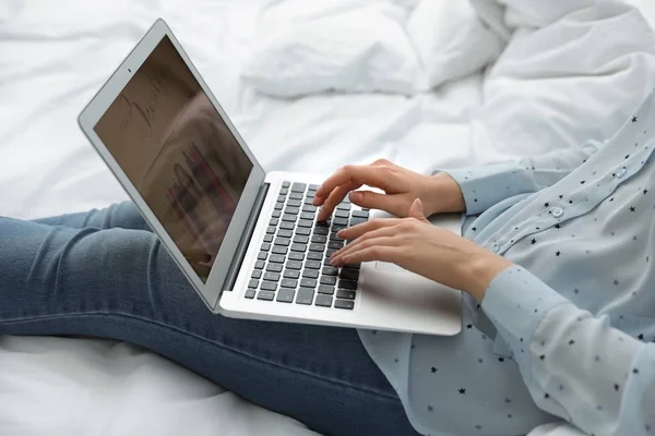 Женщина держит ноутбук с открытым сайт красоты на кровати, крупным планом — стоковое фото