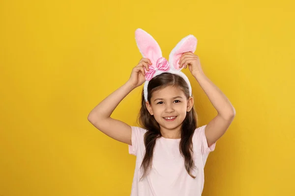 Portrait of little girl in Easter bunny ears headband on color background — Stock Photo, Image