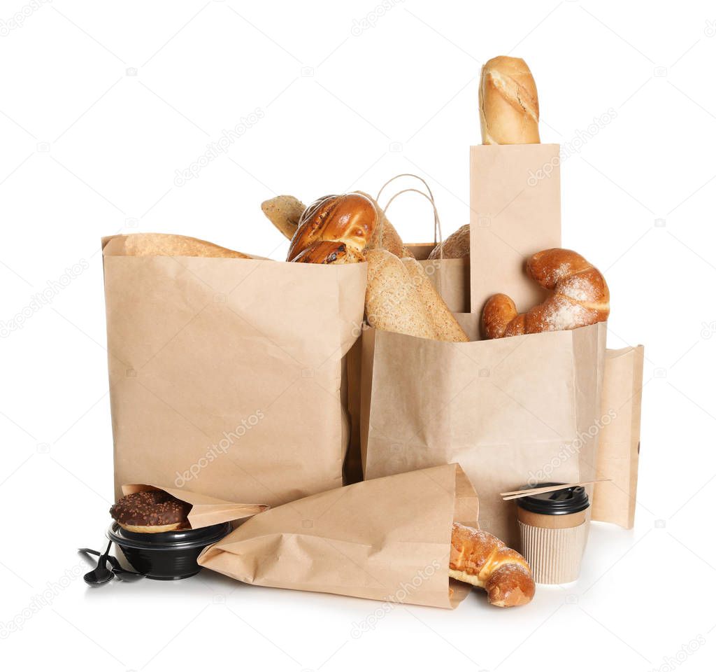 Different fresh bakery products in paper bags on white background