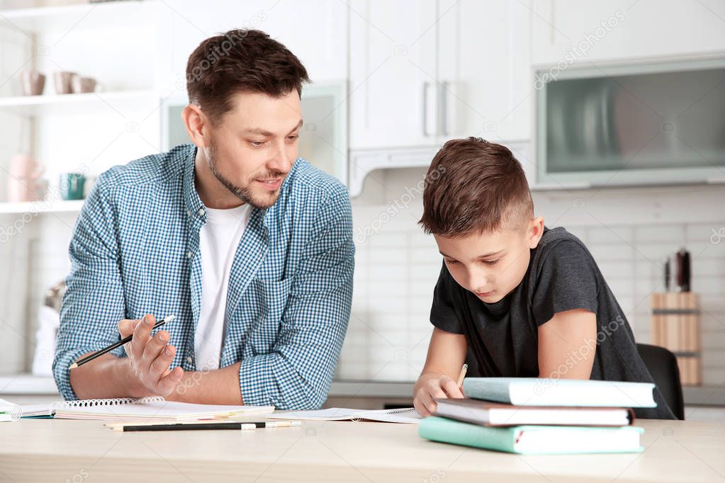 Dad helping his son with homework in kitchen
