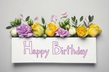 Güzel çiçek açan çiçekler ve açık renkli mutlu doğum günü kartına düz yatıyordu kompozisyonu